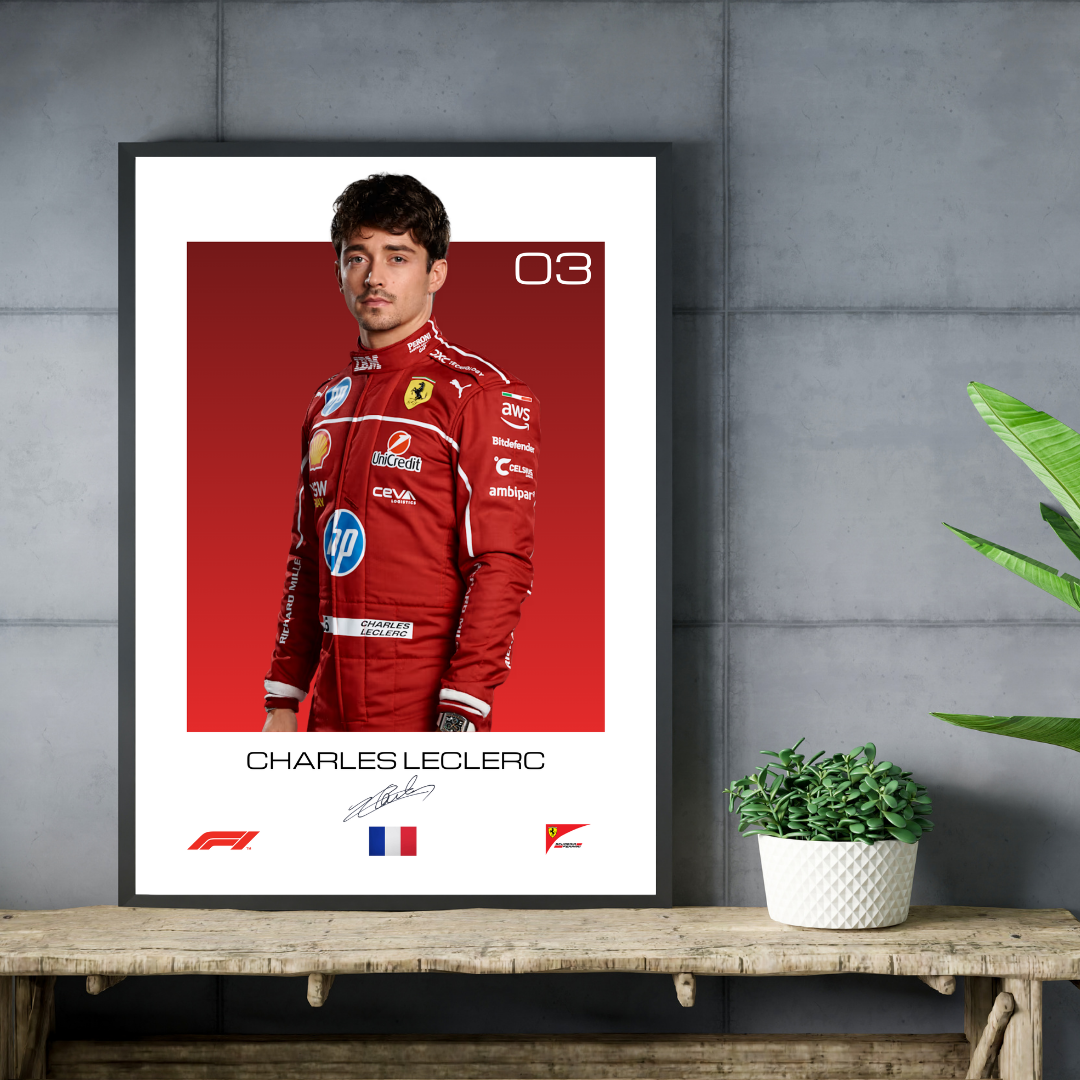 Framed poster of Charles Leclerc in a red racing suit on a white background, leaning against a gray wall with a plant.