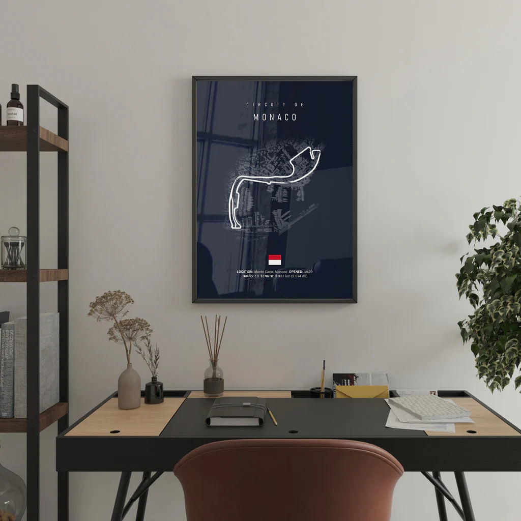 Framed poster of the monaco race track layout on a wall above a desk.