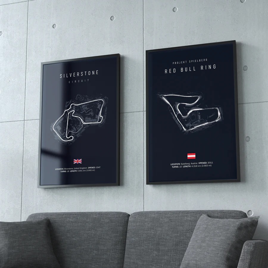 Two framed posters of race track layouts on a wall above a gray sofa.