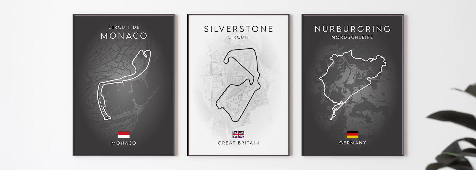 Three framed maps of Circuit de Monaco, Silverstone Circuit, and Nurburgring Nordschleife on a wall above a sofa.